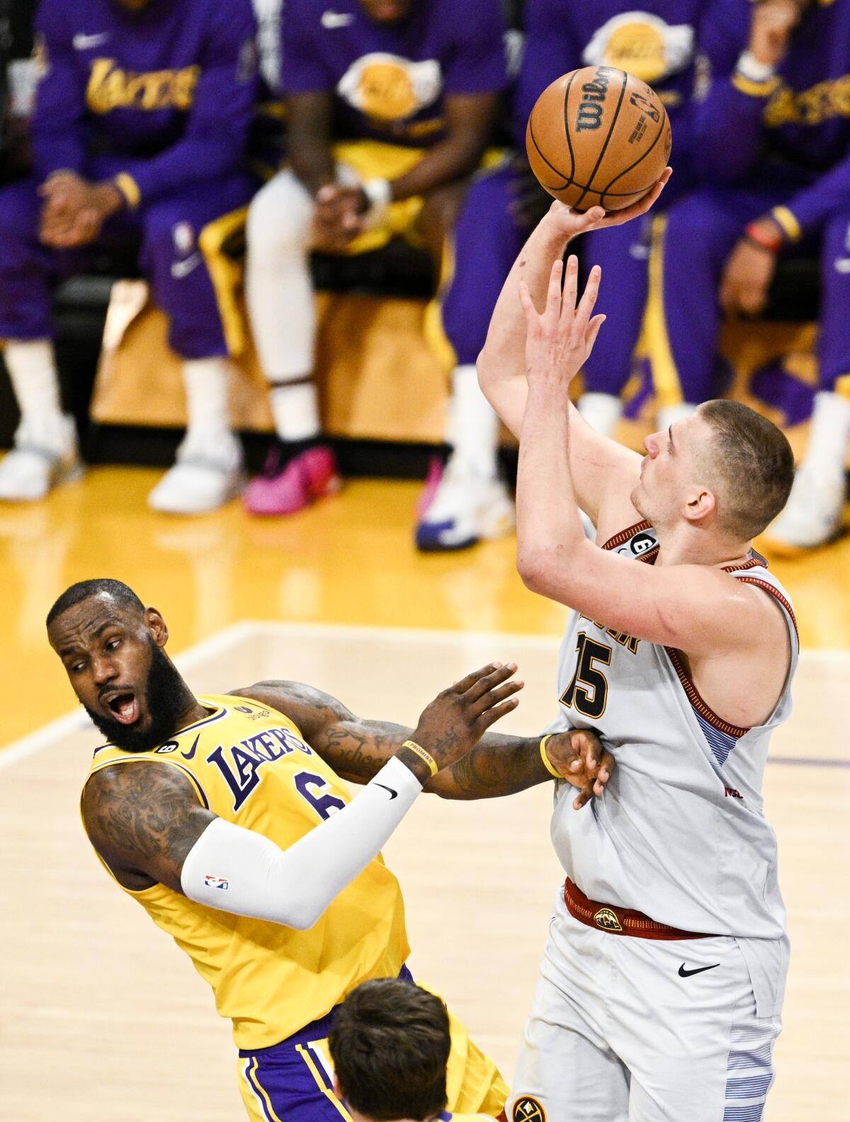 Lakers forward LeBron James, left, draws an offensive foul on Nuggets center Nikola Jokic.