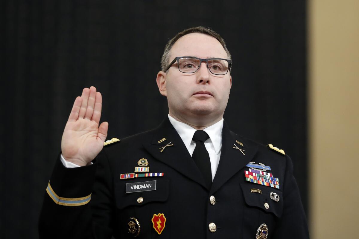 Lt. Col. Alexander Vindman stands in a decorated military uniform holding up his right hand. 