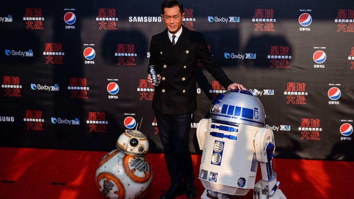 Hong Kong actor and film producer Louis Koo poses with droids BB-8, left, and R2-D2 on the red carpet for the Chinese premiere of "Star Wars: The Last Jedi" at the Shanghai Disney Resort on Dec. 20, 2017.