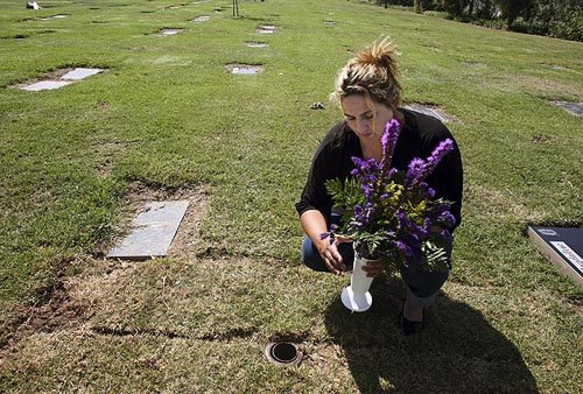 Melinda Wall places fresh flowers on the graves of her grandfather and mother. Wall's mother, Maria Elena Hicks, was shot and killed earlier this month after confronting a youth spraying graffiti on a wall in her Pico Rivera neighborhood. Her daughter says that she will maintain the grave weekly.