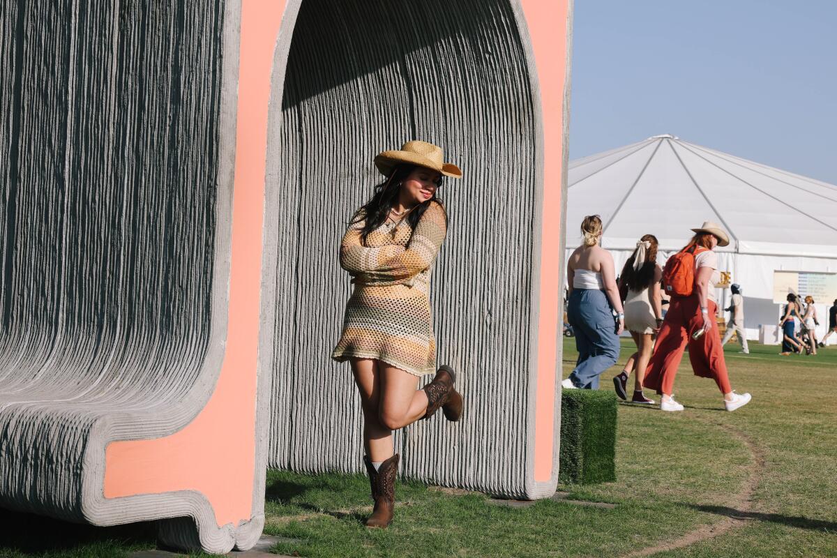 Woman in a cowboy hat and boots poses with art installation at Coachella