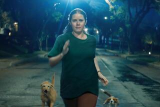 A woman runs down a street at night flanked by dogs.