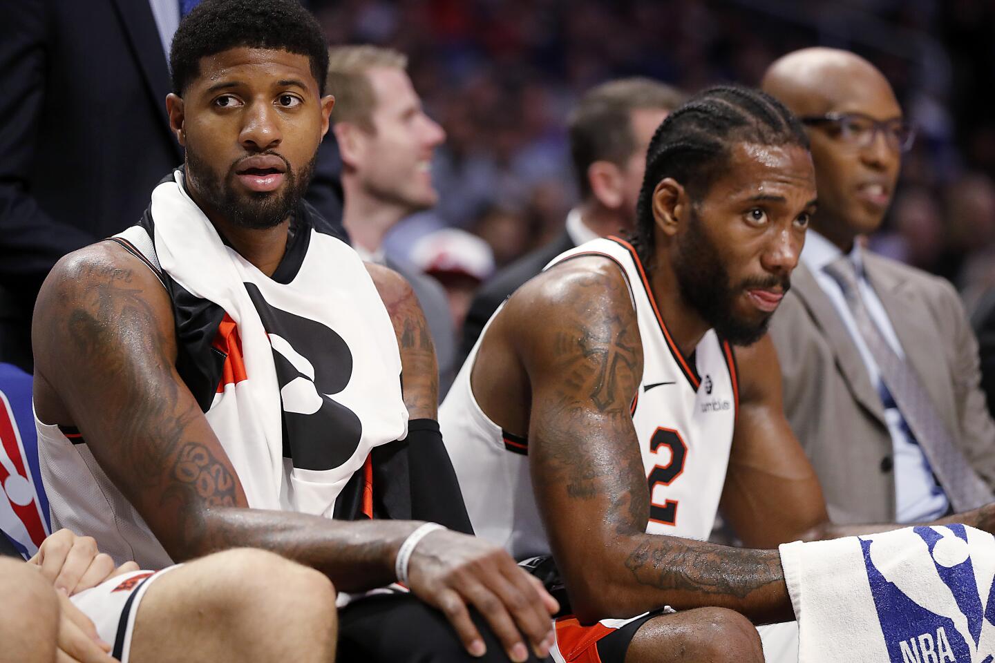 Clippers stars Paul George, left, and Kawhi Leonard rest on the bench in the fourth quarter at Staples Center on Tuesday.
