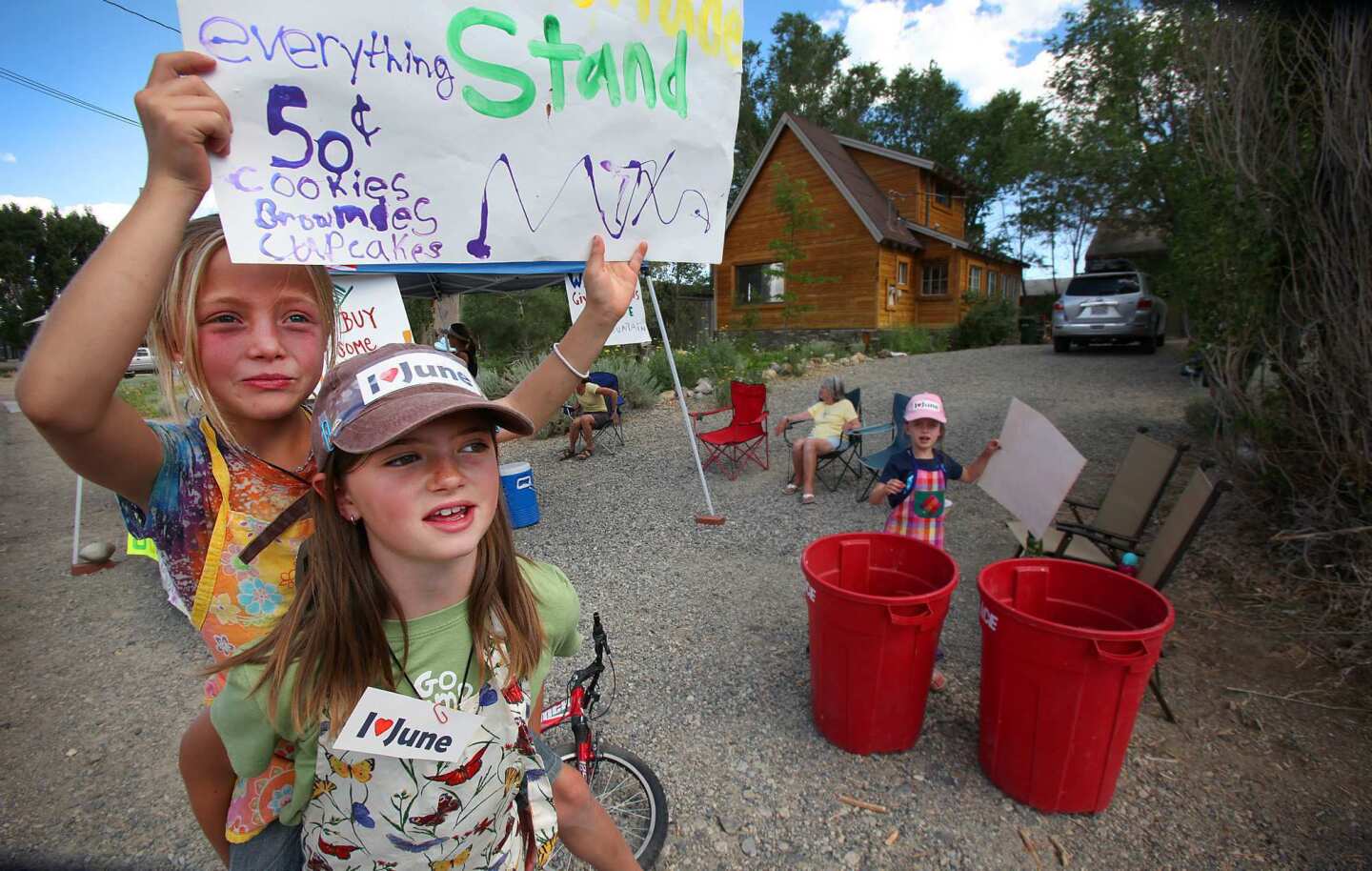 Jordyn Harper, 9, left, holds a sign with Caelen McQuilkin, 10, and Laurel Satterfield, 8, right, as they help sell lemonade and baked goods to raise money and awareness for June Mountain. The Eastern Sierra town of June Lake is predicting hard times now that the operator of Mammoth Mountain has decided to close June Mountain ski resort for at least one year.