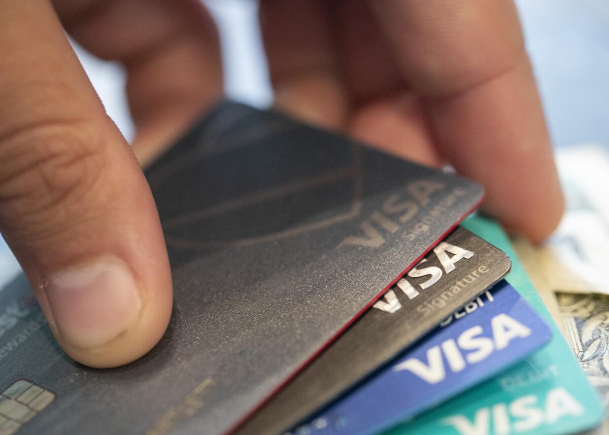 A hand holds Visa credit cards