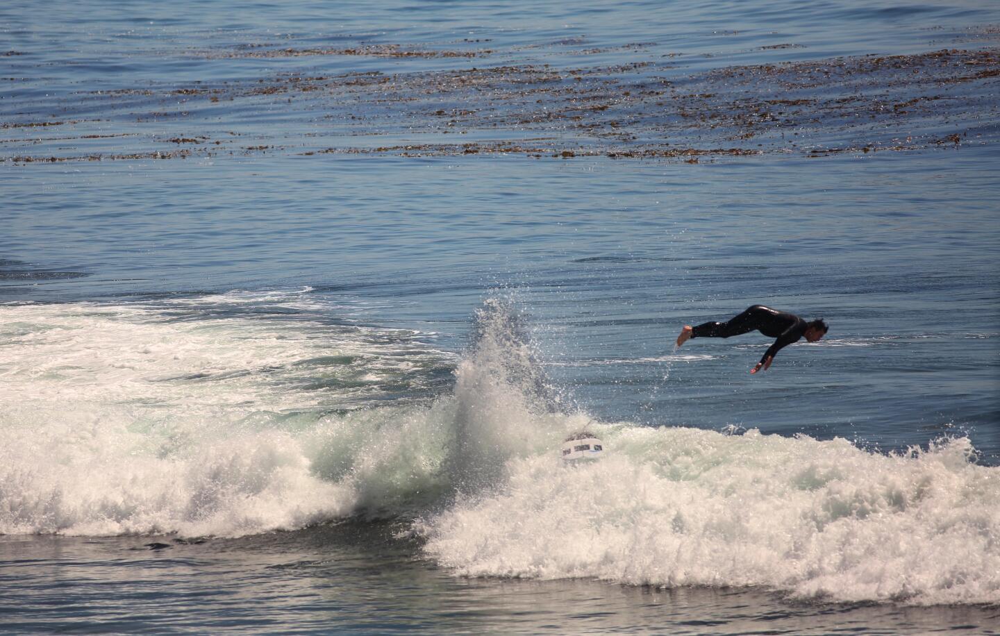 A surfer hangs ten and a bit more while catching waves as some tried to regain some semblance of normality during days of the coronavirus pandemic at Point Mugu State Park in Ventura County Ventura on Wednesday, April 15, 2020. Point Mugu State Park has been temporarily closed since April 7 in an effort to prevent visitation surges to help stop the spread of the coronavirus. (Genaro Molina / Los Angeles Times)