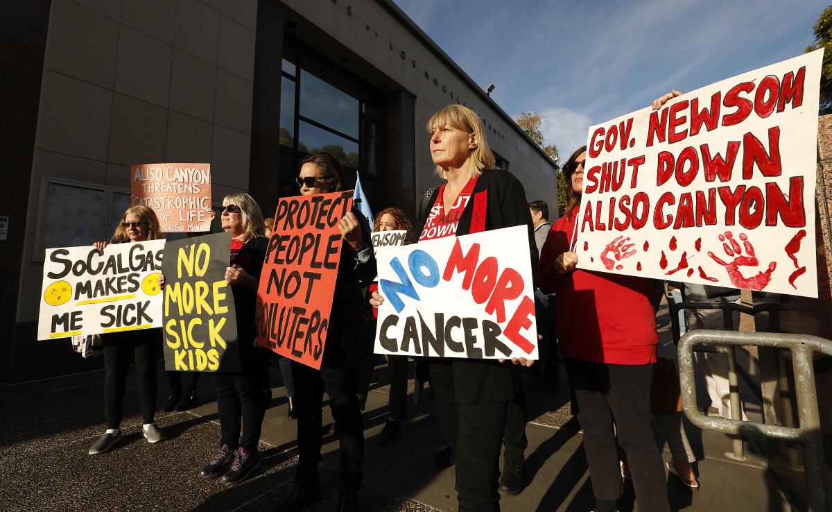 Protesters hold signs including "SoCalGas Makes Me Sick" and "Gov. Newsom Shut Down Aliso Canyon."