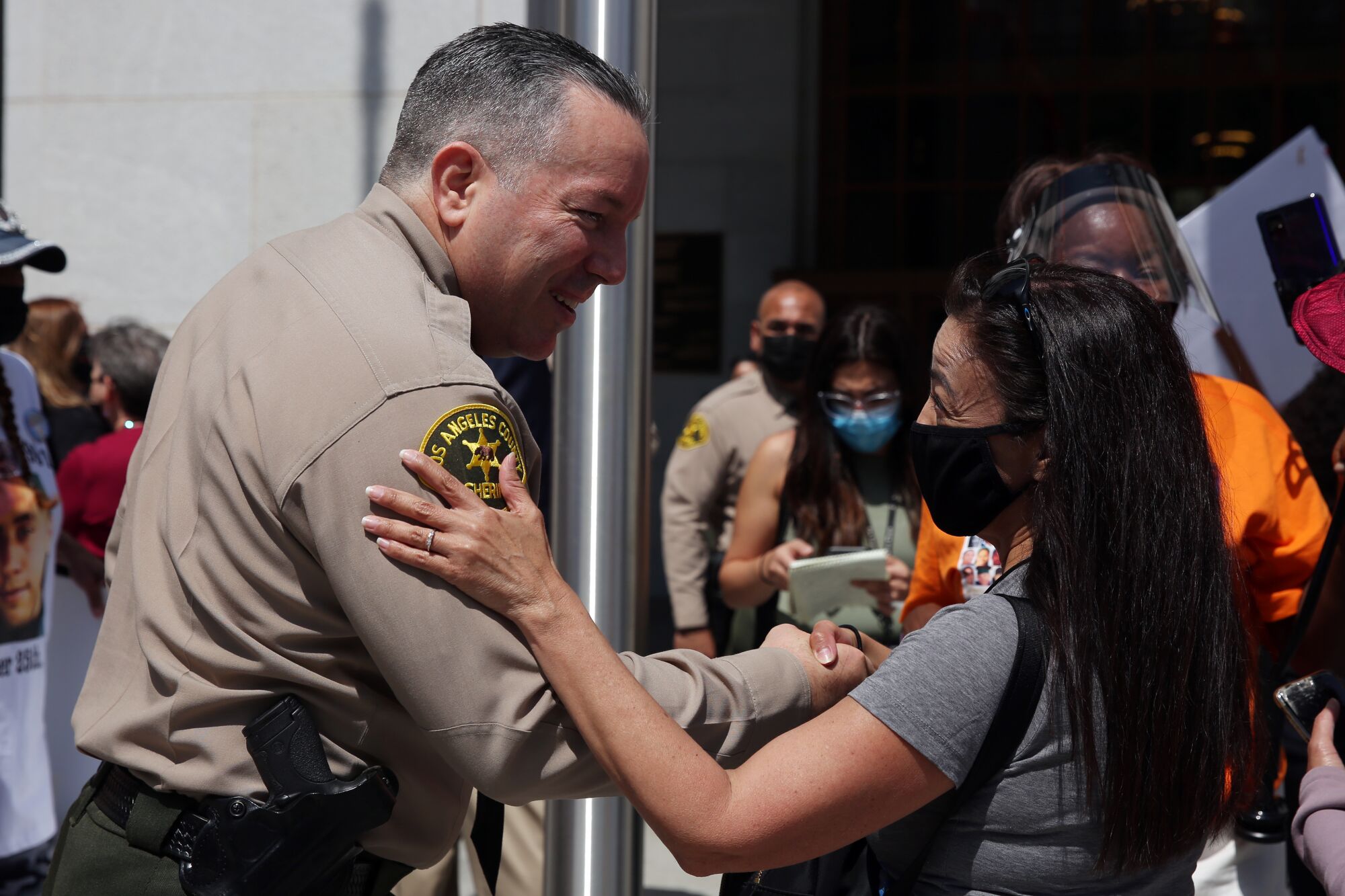 Alex Villanueva smiles and shakes a woman's hand