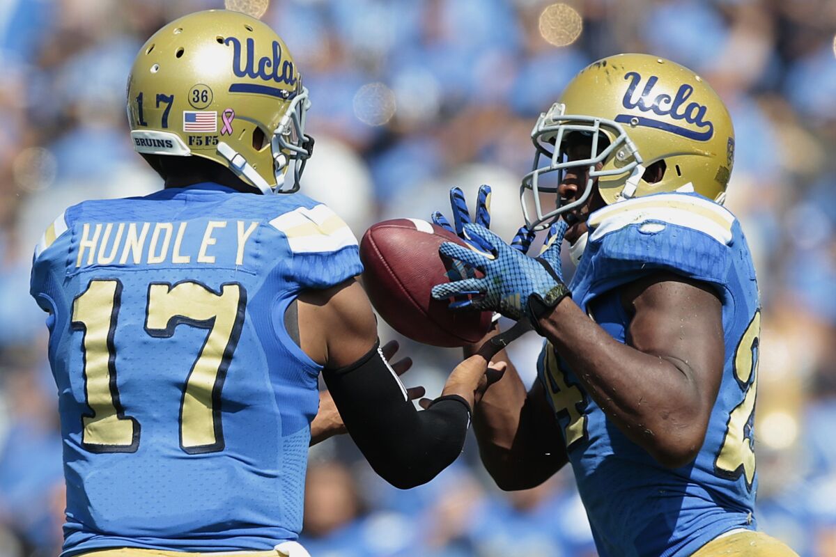 Bruins quarterback Brett Hundley and running back Paul Perkins try to gather a bad snap in the first quarter.