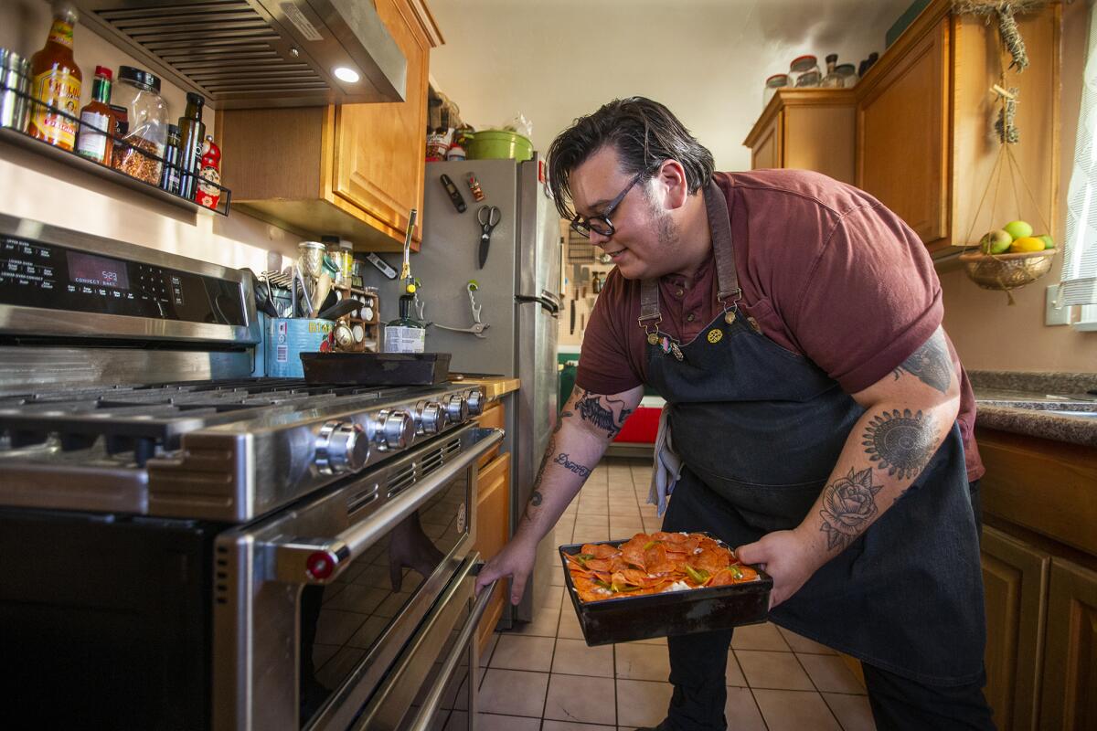 Derek Bracho puts a homemade focaccia bread pizza into the oven at his home in Anaheim on Thursday, Sept. 30.