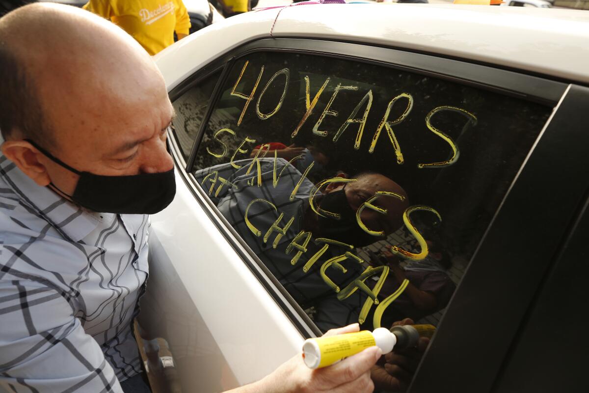 Valet worker Carlos Barrera writes a message on his car window in support of Chateau Marmont employees who lost their jobs.