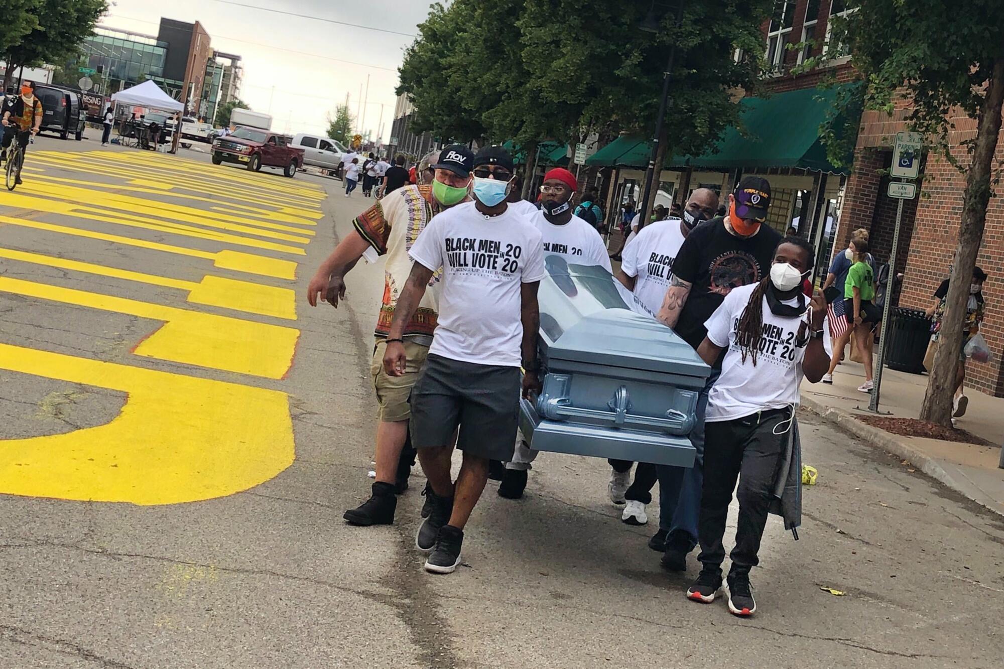 Volunteers carry an empty coffin past a new Black Lives Matter in Tulsa, Okla., for Juneteenth. 