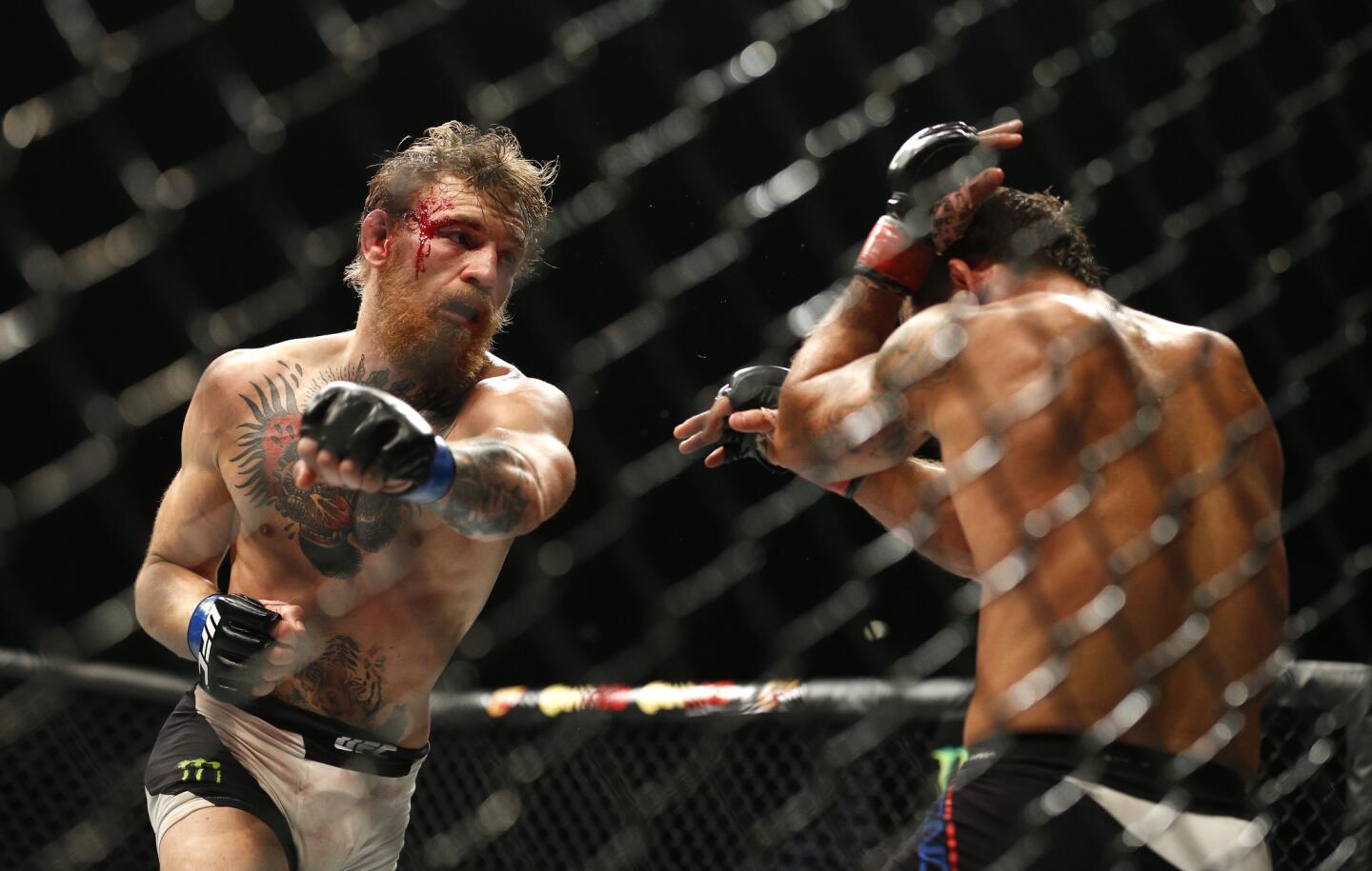 Conor McGregor, left, takes a swing at Chad Mendes during their interim featherweight title mixed martial arts bout at UFC 189 Saturday, July 11, 2015, in Las Vegas. (AP Photo/John Locher)