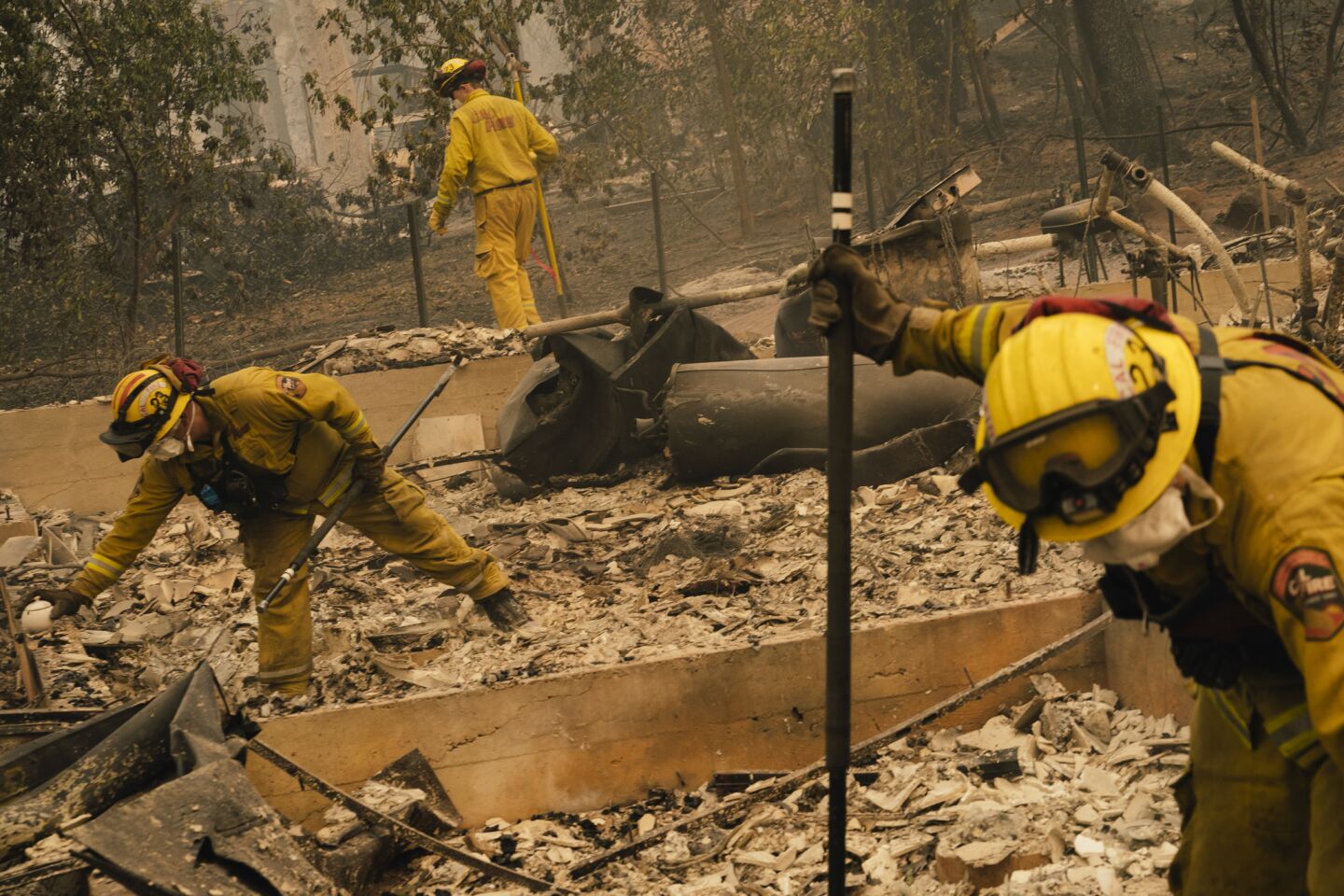 A crew from the California Department of Forestry and Fire Protection walks through the rubble of a home while putting out hot spots in Paradise, Calif.