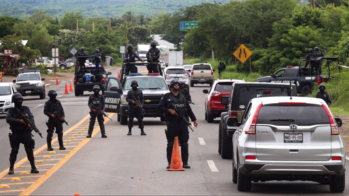 Police officers stand guard at a checkpoint near Nayarit, Mexico, on Wednesday after the kidnapping this week of a son of Sinoloa cartel head Joaquin "El Chapo" Guzman.