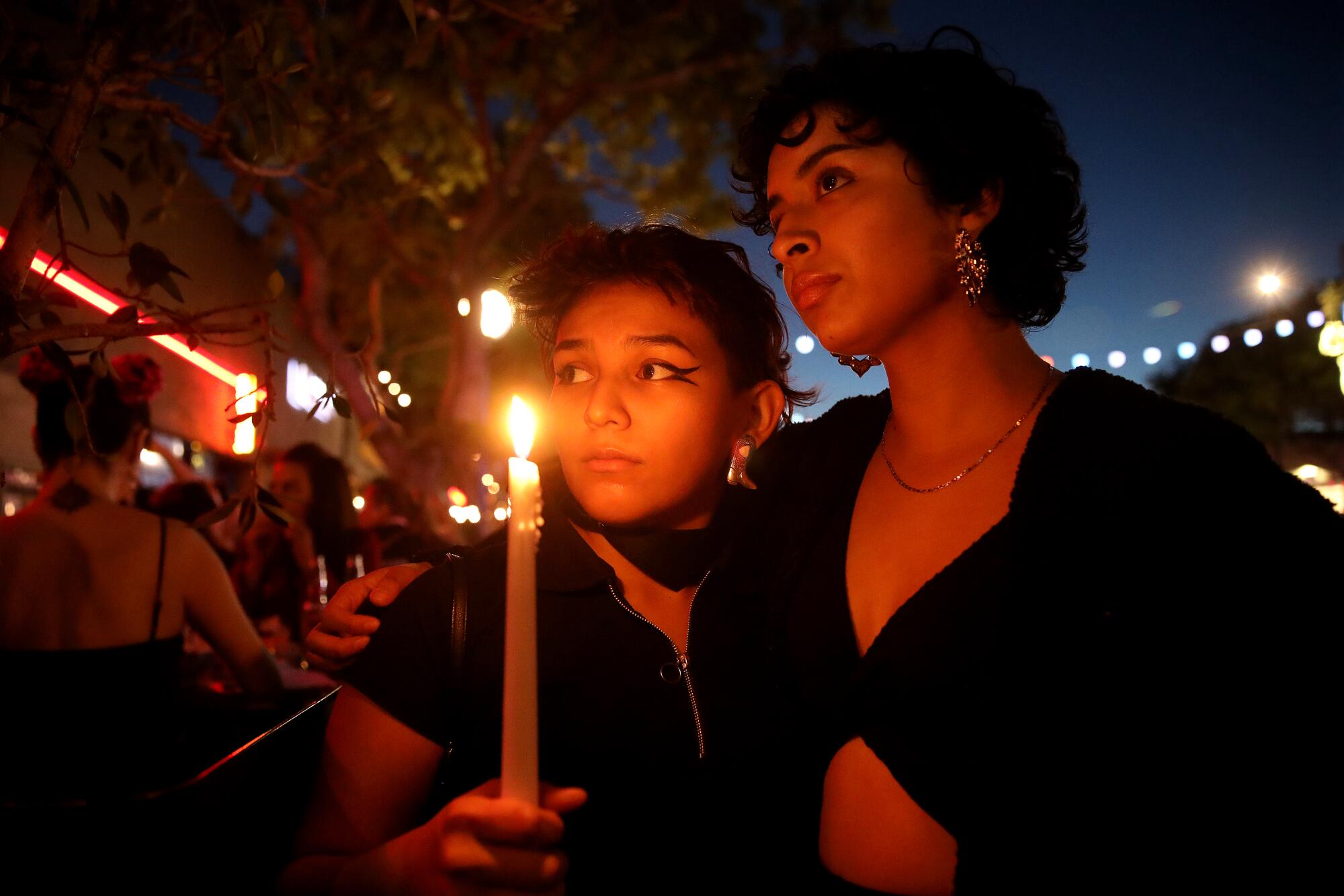 Two women attend a candlelight vigil in Los Angeles for victims of the Club Q shooting in Colorado Springs, Colo.