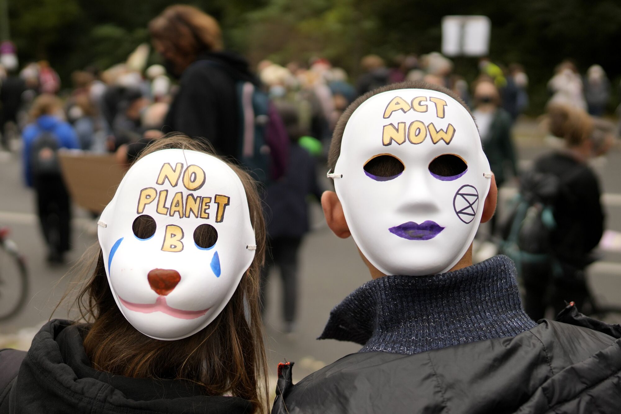 Masks at a rally read "No planet B" and "Act now."