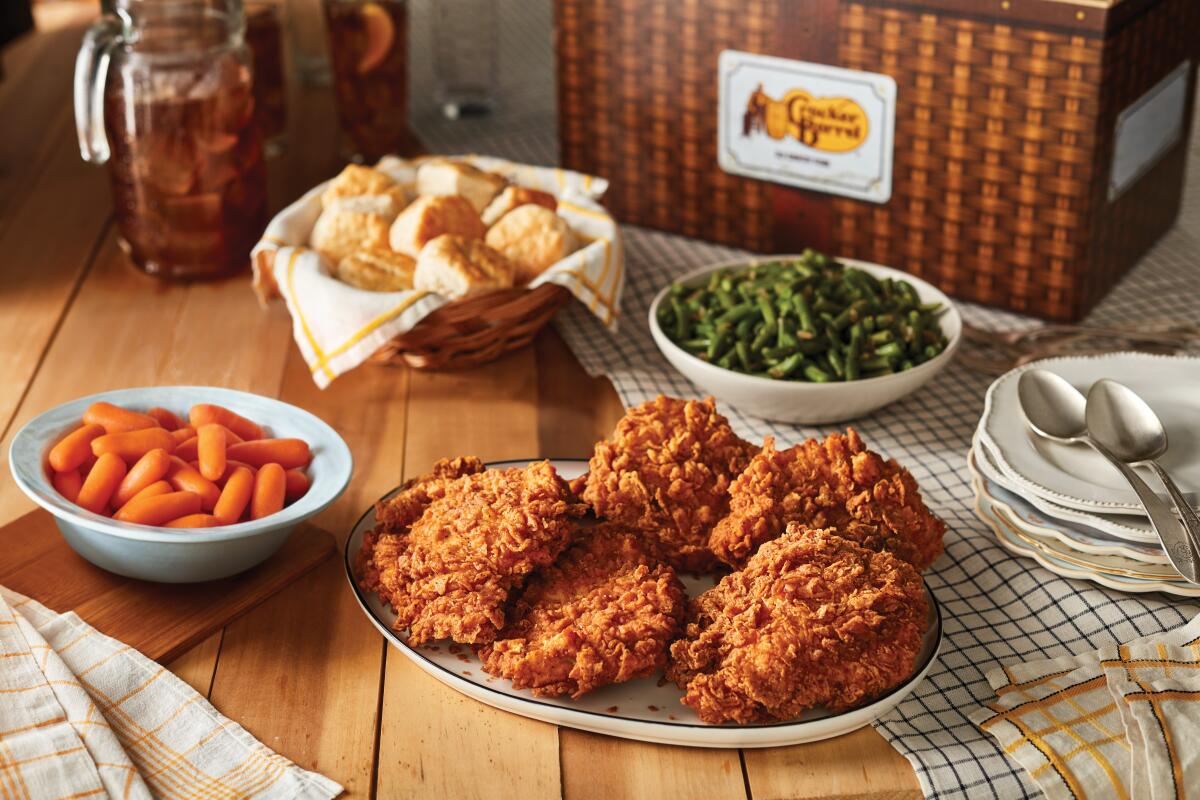 Plates of fried chicken, green beans, carrots and biscuits — all offerings from Cracker Barrel — sit on a table.  