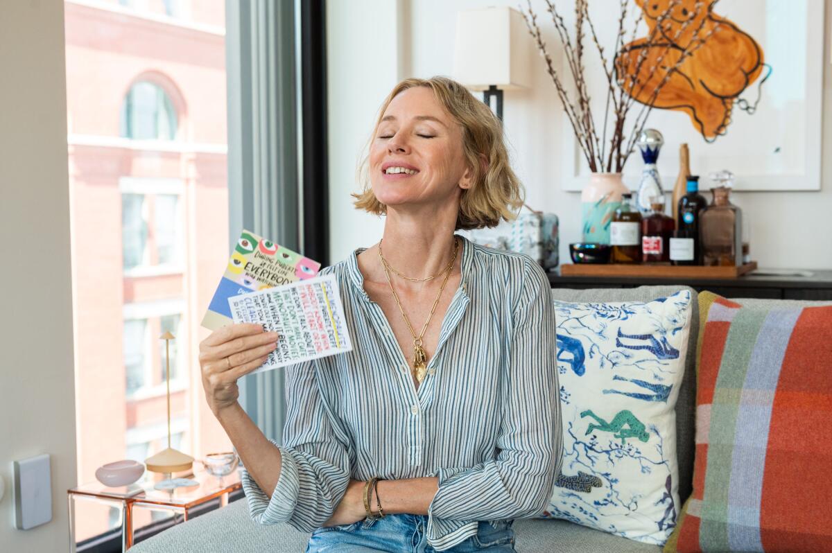 Naomi Watts fanning herself with menopause-themed greeting cards
