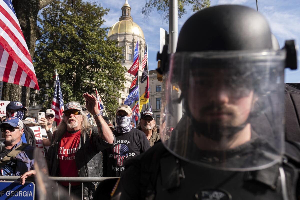 A riot officer stands between supporters of President Trump and counterprotesters outside of the state Capitol in Atlanta.