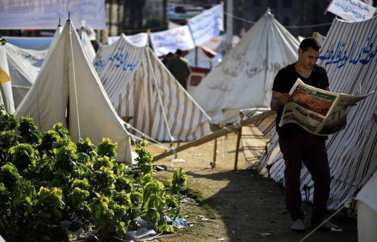 An Egyptian protester reads a newspaper next to tents pitched in Cairo's Tahrir Square. Supporters of President Mohamed Morsi plan to hold a major rally this weekend.