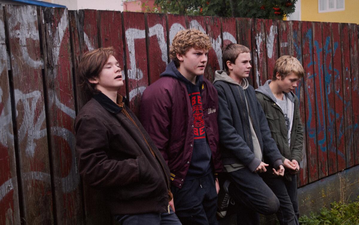 Four teenage boys lean against a graffiti-covered fence in the movie "Beautiful Beings."
