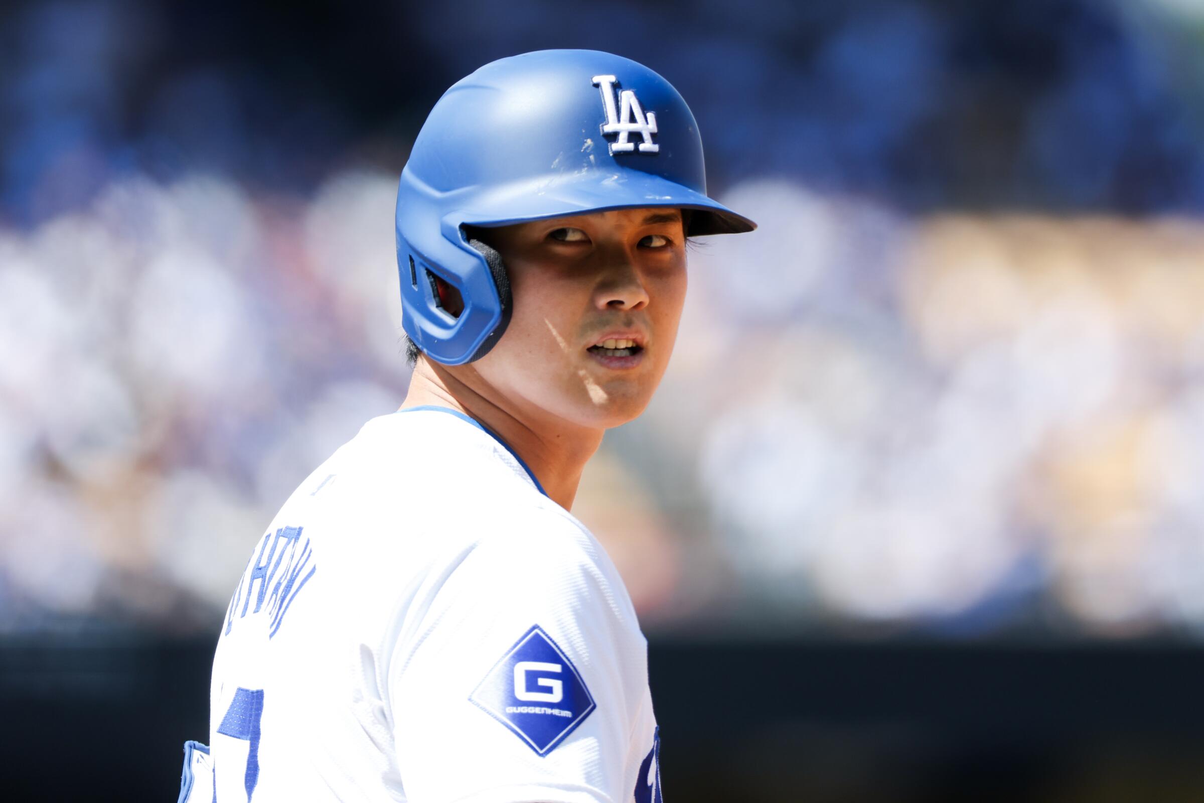 Dodgers designated hitter Shohei Ohtani looks over his shoulder from first base during the season opener.