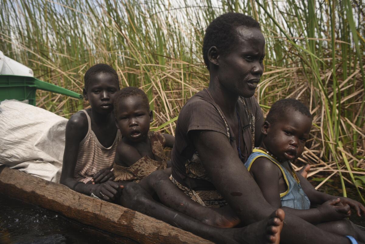 A displaced woman and her children ride in a wooden canoe through a swamp on Oct. 11, 2015, where the thick reed marshes protect against attacks, as they flee from Kok Island in Leer county to Nyal in Panyijar county.