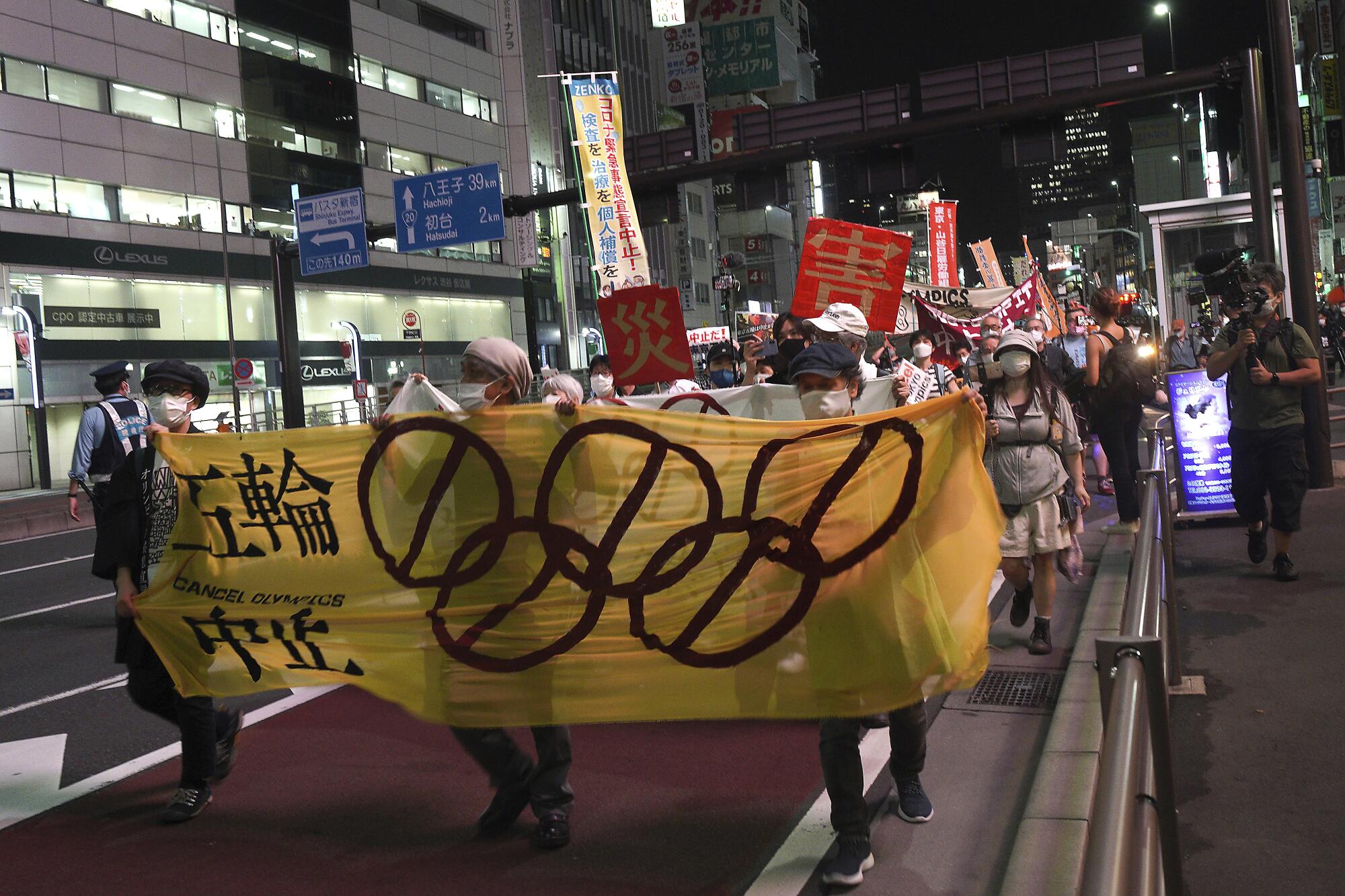 People march at night with banners and signs.