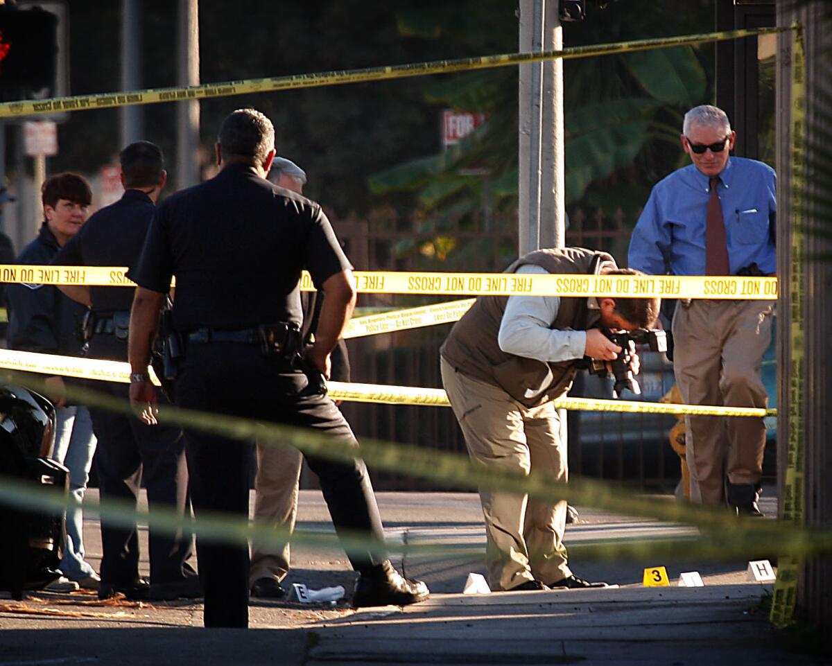Police and forensic specialists at the scene of a shooting Monday in Koreatown that left two people dead.