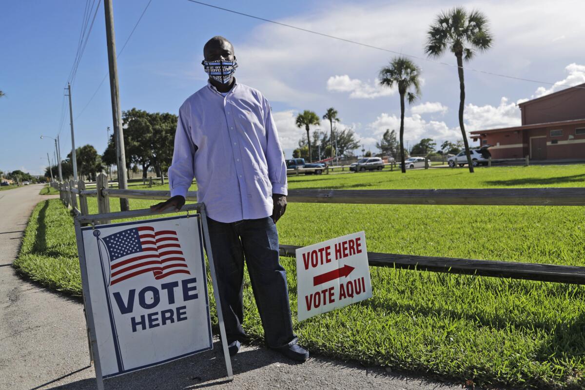 William Freeman, 51, poses near "Vote here" signs outside his polling station in Riviera Beach, Florida