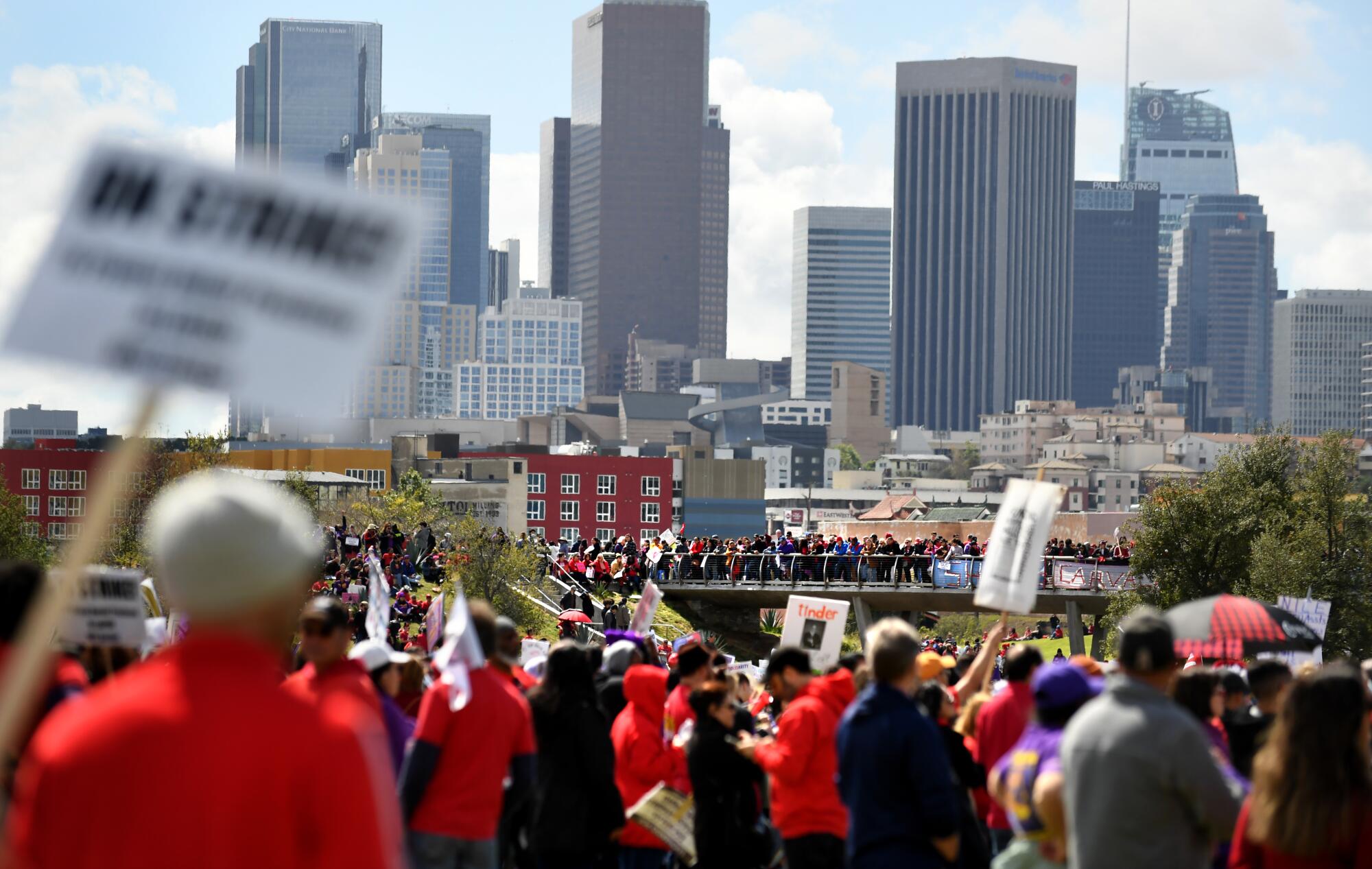 Protesters stand on a hill with downtown L.A. in the background at Los Angeles Historic State Park.