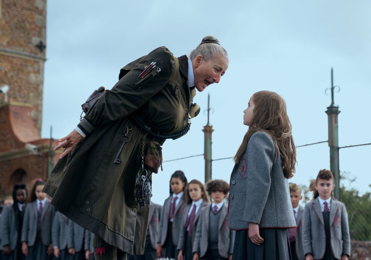 An older woman with a bun yells at a little girl as other kids look on in the movie "Roald Dahl's Matilda the Musical."