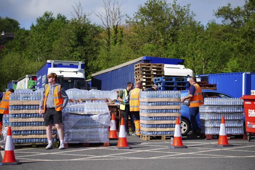 People collect bottled water at Broadsands Car Park in Paignton, England, Friday May 17, 2024. Around 16,000 households and businesses in the Brixham area of Devon have been told not to use their tap water for drinking without boiling and cooling it first, following the discovery of small traces of a parasite in the local water network. (Ben Birchall/PA via AP)