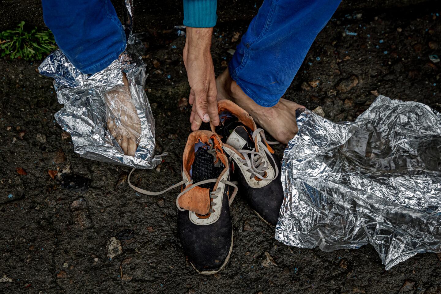 A Venezuelan man stuffs his shoes with makeshift socks made of strips of emergency blankets after leaving a shelter in Pamplona, Colombia.