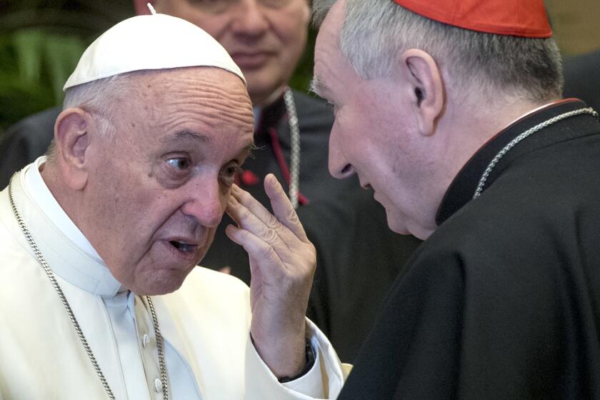 FILE - In this Dec. 21, 2017 file photo, Pope Francis talks to Vatican Secretary of State, Cardinal Pietro Parolin, on the occasion of his Christmas greetings to the Roman Curia in the Clementine Hall at the Vatican. Pope Francis summoned the secretary of state, Cardinal Pietro Parolin, his deputy as well as the Vatican’s top finance official, for a meeting Wednesday, Nov. 4, 2020, and gave the Vatican secretariat of state three months to transfer all its financial holdings to another Vatican office following its bungled management of hundreds of millions of euros in donations and other assets that are now the subject of a corruption investigation. (Claudio Peri/pool photo via AP)