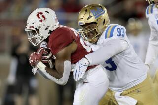 UCLA defensive lineman Jay Toia wraps up Stanford running back E.J. Smith 