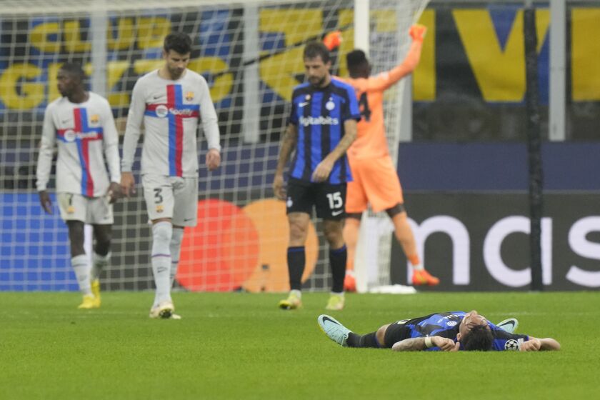 Lautaro Martínez del Inter de Milán tirado en el piso al celebrar la victoria 1-0 ante el Barcelona en la Liga de Campeones en el Milán, el martes 4 de octubre de 2022. (AP Foto/Luca Bruno)