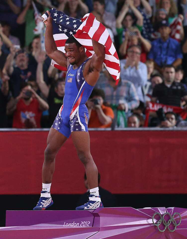 Jordan Burroughs of the United States jumps on the victory podium and celebrates his defeat of Iran's Sadegh Saeed Goudarzi to win the men's wrestling gold medal.