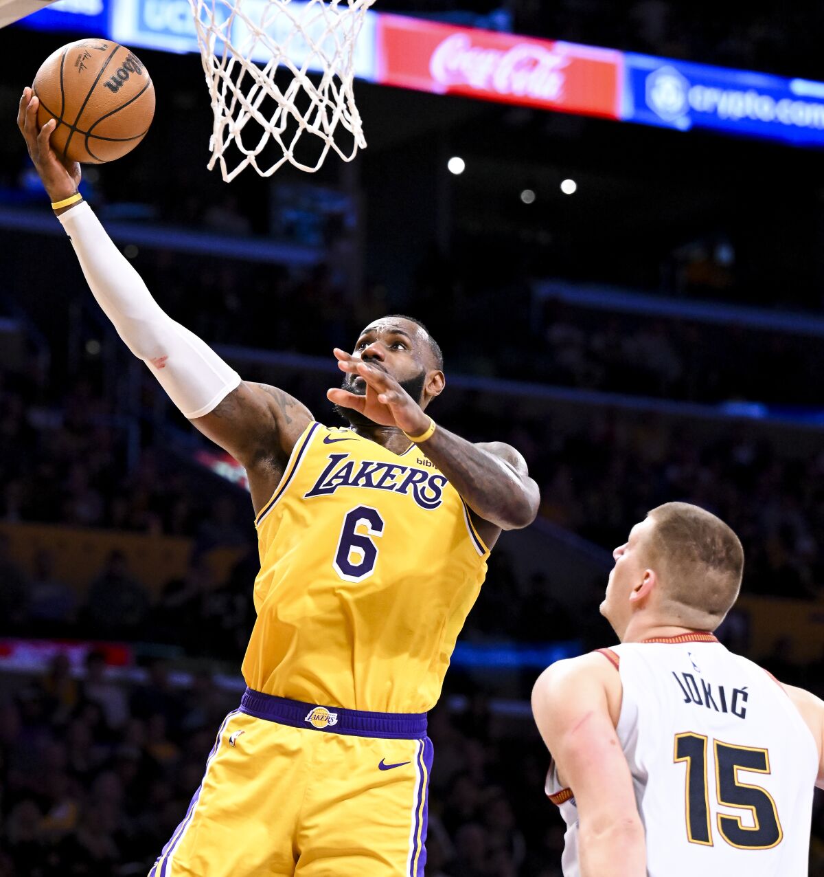 Lakers forward LeBron James, left, scores on a layup over Nuggets center Nikola Jokic.