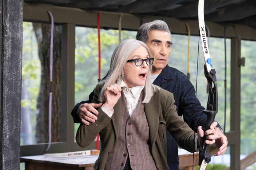 A woman and a man do archery together.