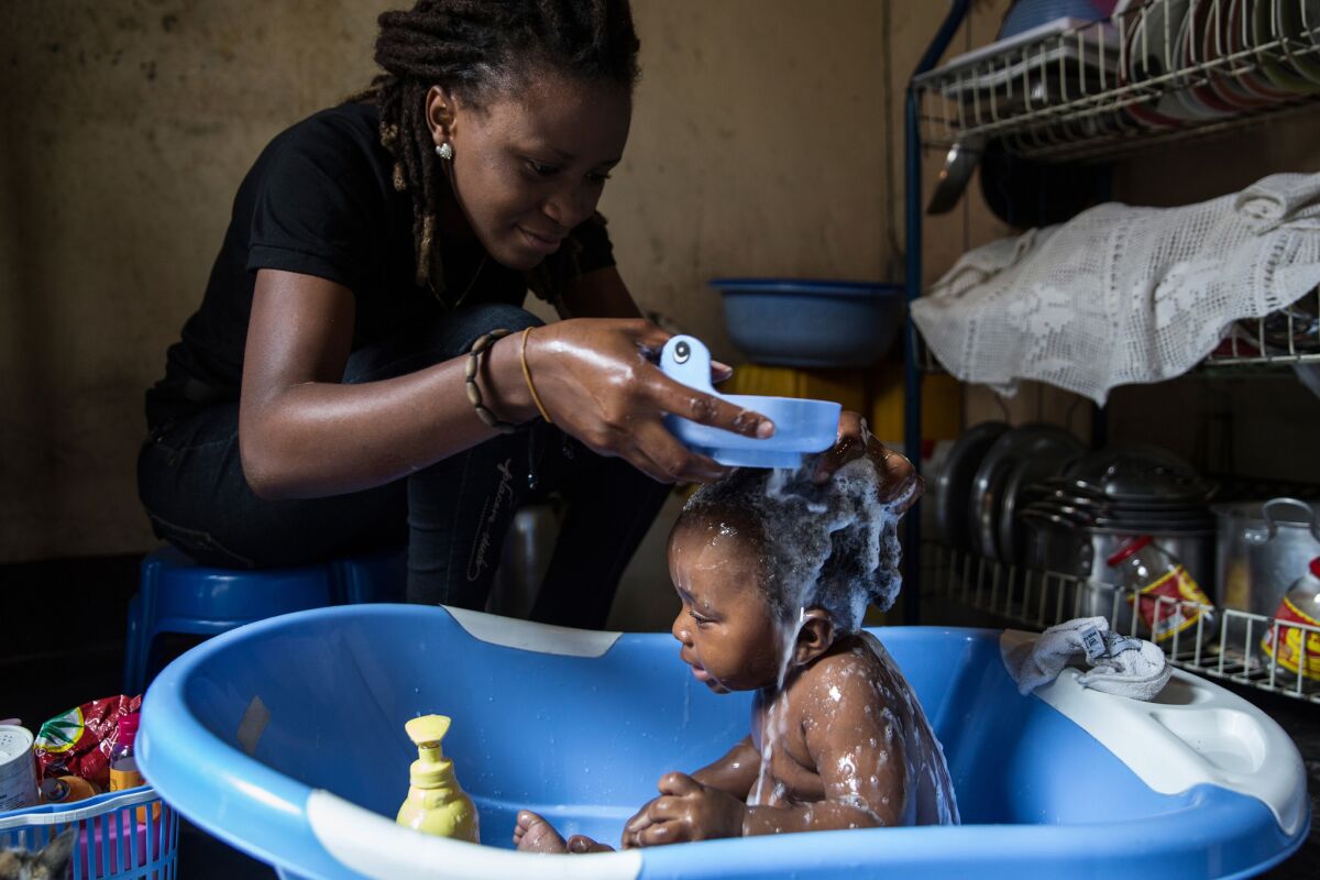 Eunice Etaka gives her nephew Jerome a bath at her sister's home in Kinshasa. Etaka lives with her sister, brother-in-law and nephew in order to be close to the University of Kinshasa, where she studies law.