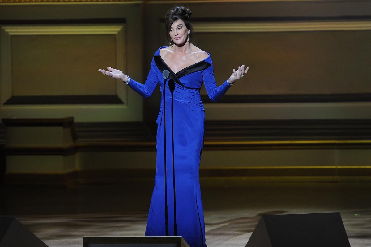Caitlyn Jenner stands on stage in a blue gown.