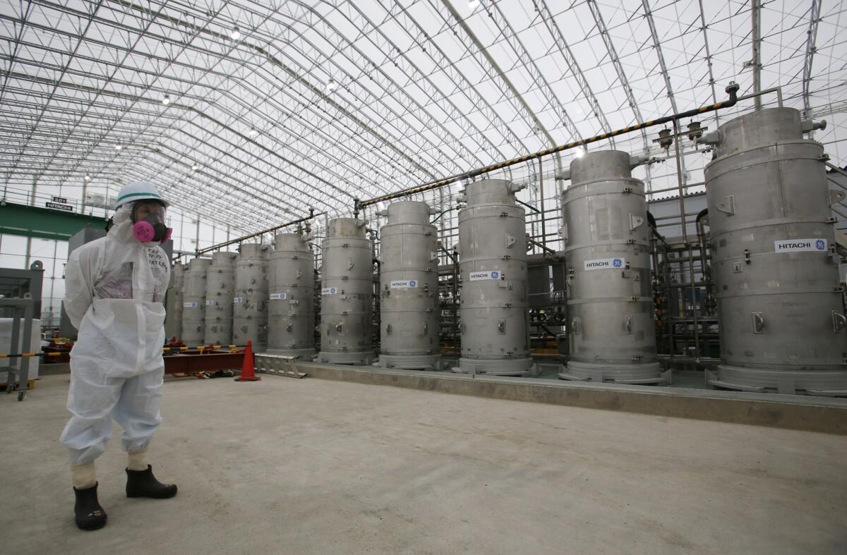 A Tokyo Electric Power Co. official stands in front of Advanced Liquid Processing Systems at the Fukushima Dai-ichi nuclear power plant.