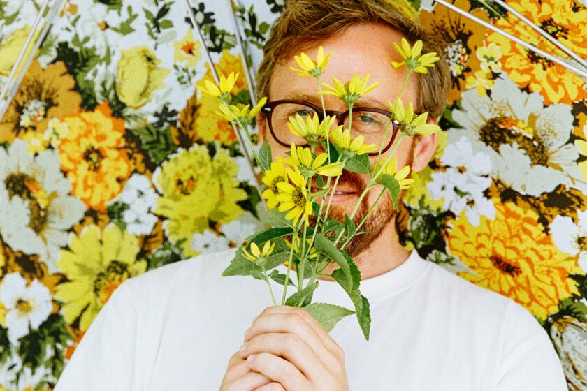 John Wilson smelling a bouquet of flowers under an umbrella.