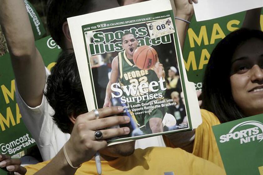 ARCHIVO - Un aficionado del equipo de baloncesto de la Universidad George Mason sostiene una revista de Sports Illustrated, el 29 de marzo de 2006, en Fairfax, Virginia. (AP Foto/Lawrence Jackson, Archivo)