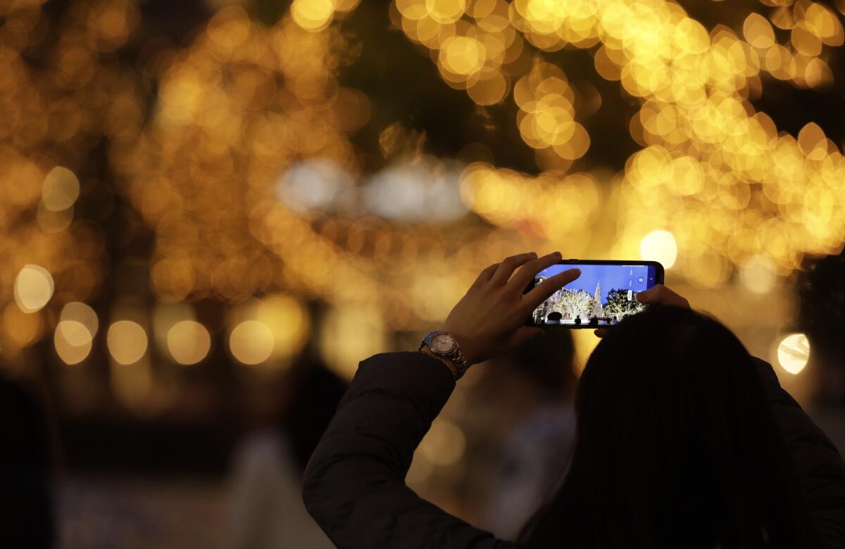 A visitor takes a picture of the 102-foot Christmas tree at The Americana at Brand in Glendale.
