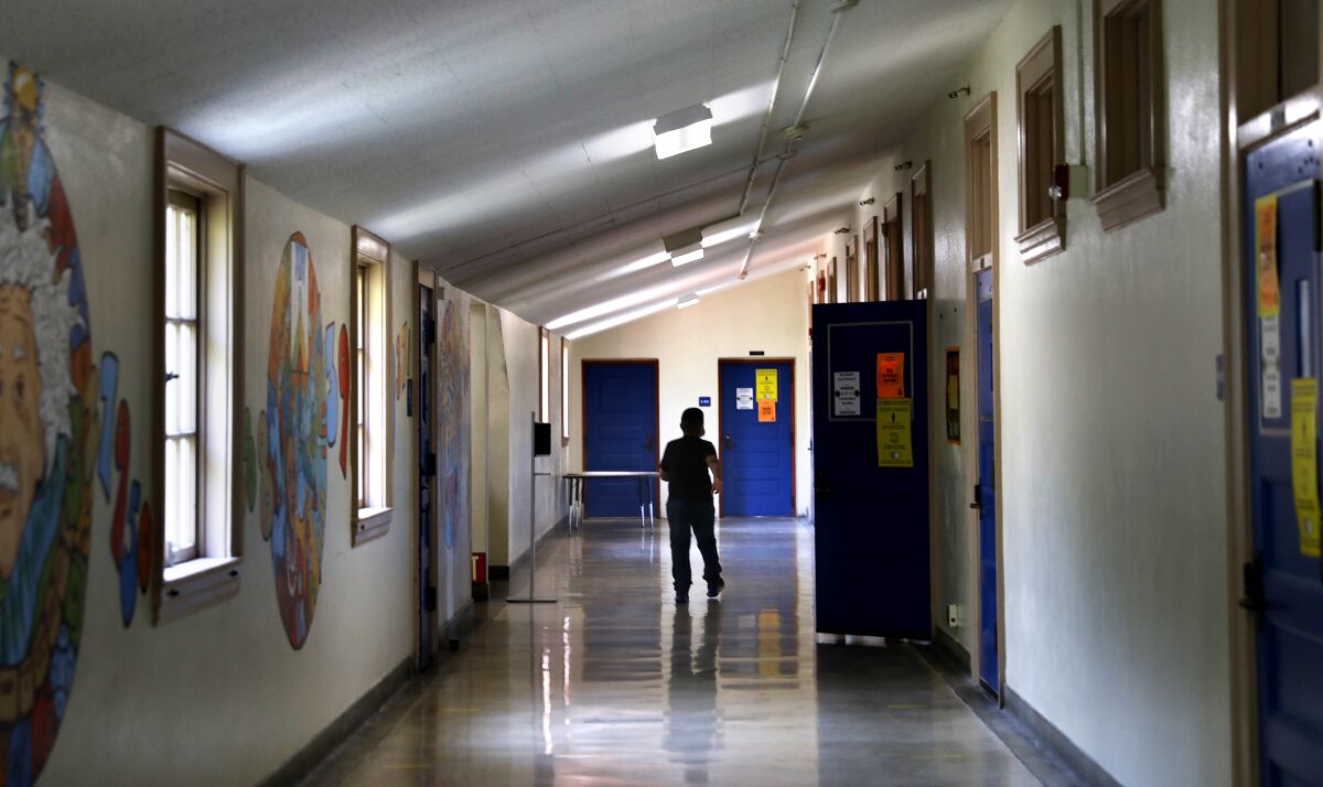 The silhouette of a child walking down a school hallway.