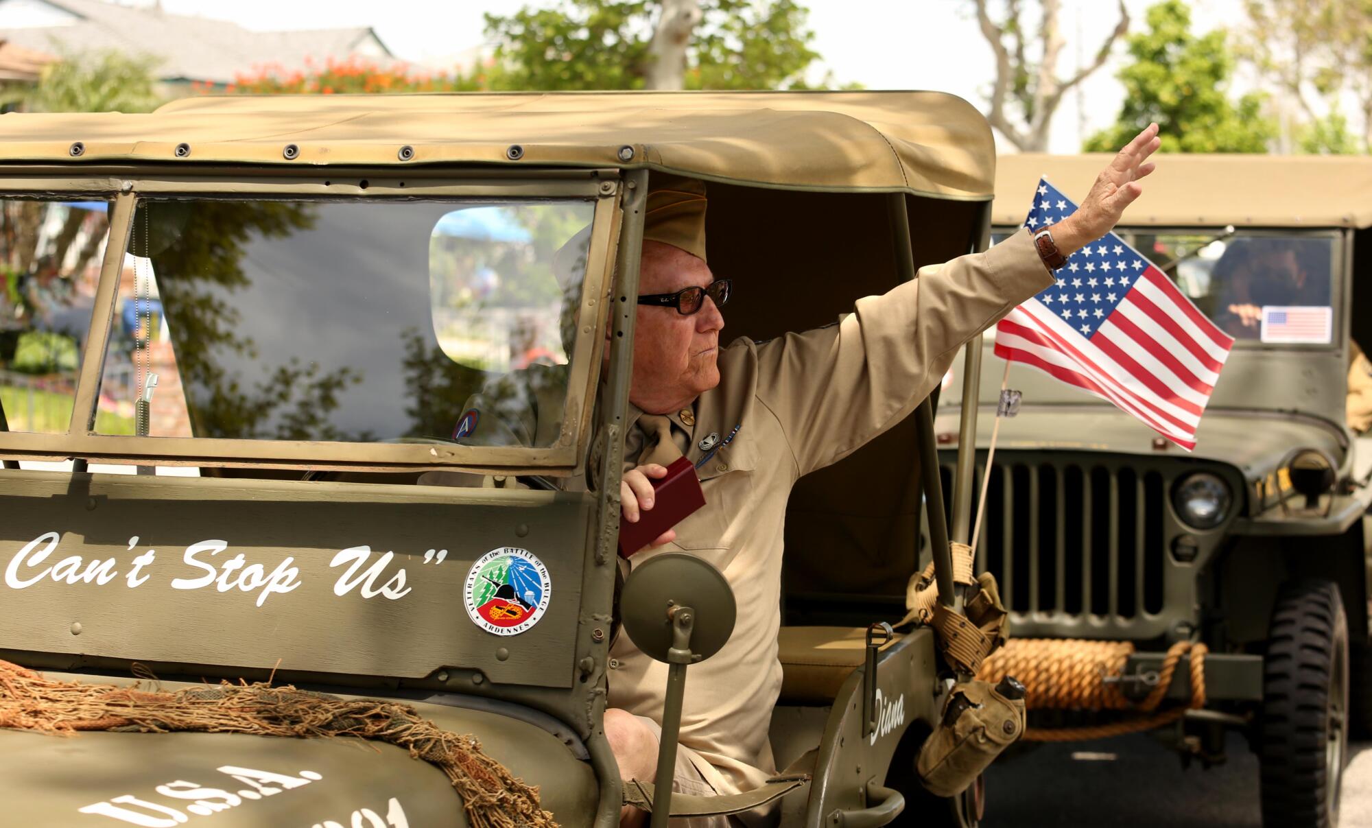 A veteran waves to World War II veteran Lt. Col. Sam Sachs during a birthday parade in Lakewood on April 26.