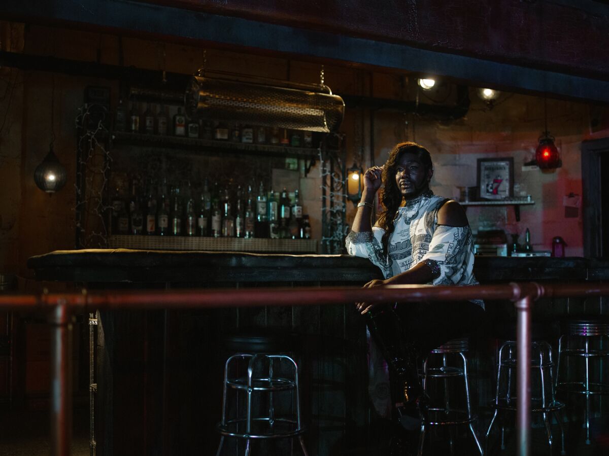 A person sits at a dim bar looking contemplative